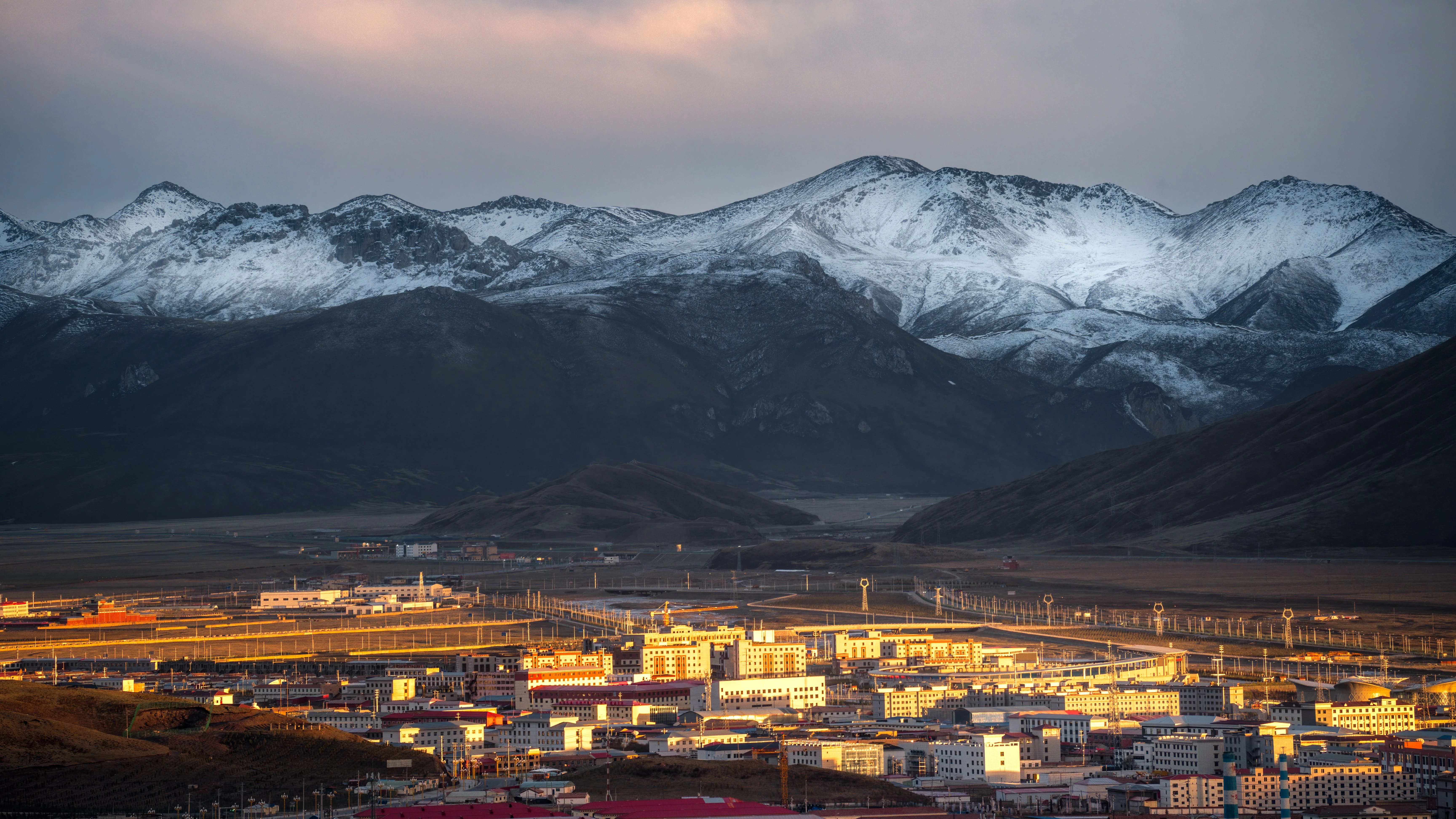 Ville tib&eacute;taine sur le plateau avec montagnes dor&eacute;es &agrave; l'aube